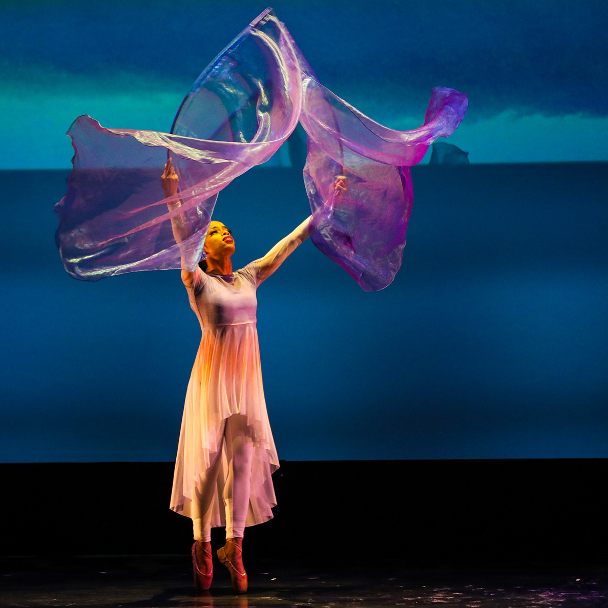 dancer twirling purple silks on stage.