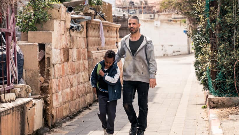 young boy and man walking down street in tel aviv